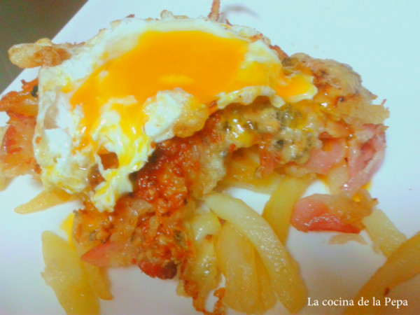 Huevos rotos con beicon, cebolla y quesos