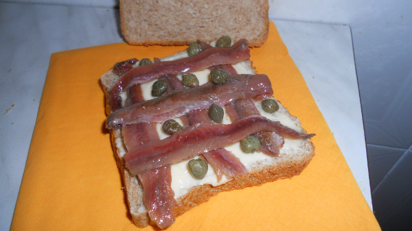 tosta de pan integral con queso anchoas y alcaparras