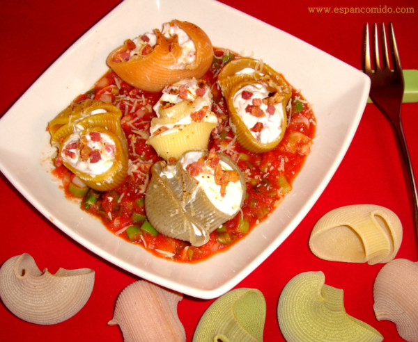 Caracolas de pasta rellenas de salsa carbonara sobre salsa de tomate